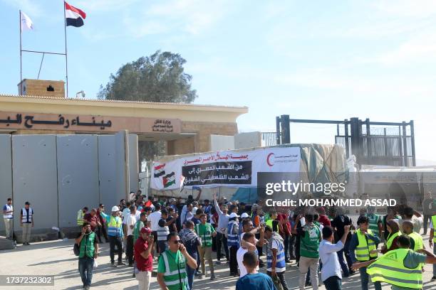 People on the Egyptian side of the Rafah border crossing watch as a convoy of lorries carrying humanitarian aid crosses to the Gaza Strip on October...