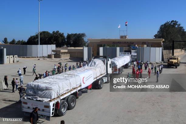 People on the Egyptian side of the Rafah border crossing watch as a convoy of lorries carrying humanitarian aid crosses to the Gaza Strip on October...