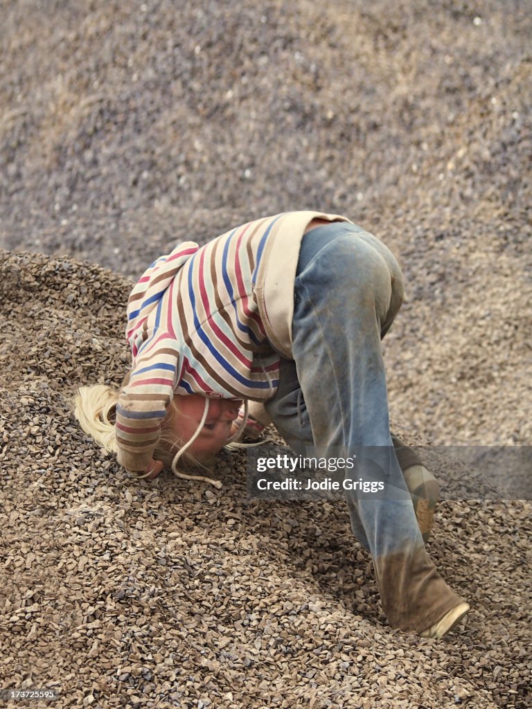 Child climbing around in pile of dirt and gravel