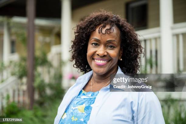 portrait of smiling black woman at home in rockaway beach - blue blouse stock pictures, royalty-free photos & images