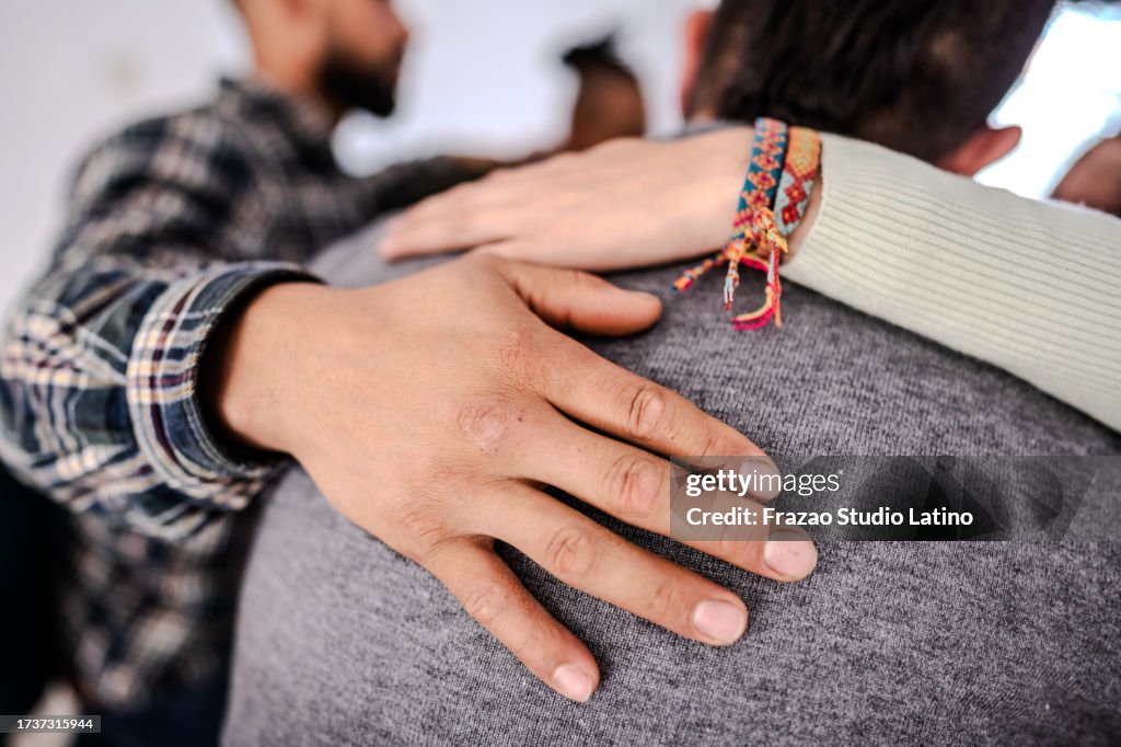 Close-up of a hand on the shoulder comforting another patient during a group therapy session