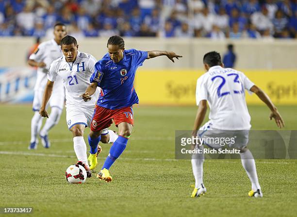 Midfielder Jean Monuma Constant of Haiti moves between forward Roger Rojas and midfielder Edder Delgado of Honduras during a 2013 CONCACAF Gold Cup...