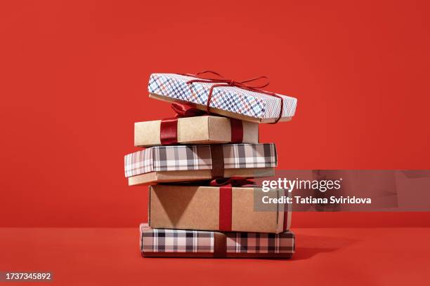 several brown gift boxes in a pile on red - geschenktüte einwickelpapier stock-fotos und bilder