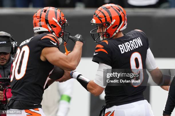 Joe Burrow of the Cincinnati Bengals hands the ball to Andrei Iosivas after he scored his first touchdown during the second quarter against the...