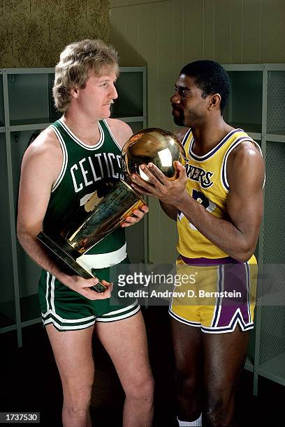 Larry Bird of the Boston Celtics poses for a portrait with Magic Johnson of the Los Angeles Lakers with each holding the NBA Championship Trophy at...