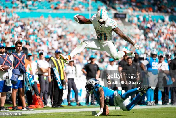 Raheem Mostert of the Miami Dolphins jumps over CJ Henderson of the Carolina Panthers during the third quarter at Hard Rock Stadium on October 15,...