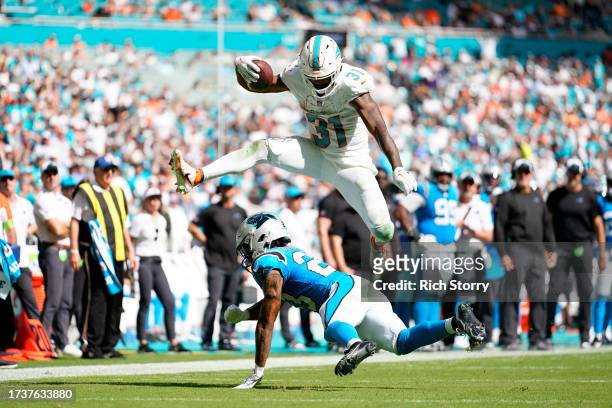Raheem Mostert of the Miami Dolphins jumps over CJ Henderson of the Carolina Panthers during the third quarter at Hard Rock Stadium on October 15,...