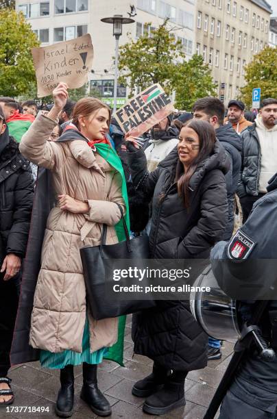 October 2023, Hamburg: Demonstrators stand in front on Steindamm in St Georg holding banners reading "Israel kills children! 1030 children in 9 days"...