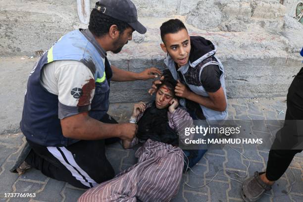 Palestinians evacuate a wounded woman after an Israeli strike near an United Nations Relief and Works Agency for Palestine Refugees school in Khan...