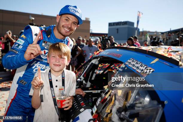 Kyle Larson, driver of the HendrickCars.com Chevrolet, and son, Owen Larson pose with the winner sticker on his car in victory lane after winning the...