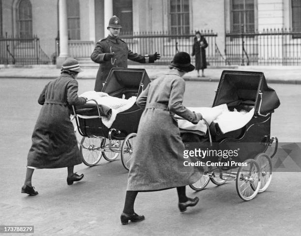 The infant Princess Alexandra of Kent and her brother, Prince Edward, Duke of Kent, with their nannies on an outing in their prams, 1937.