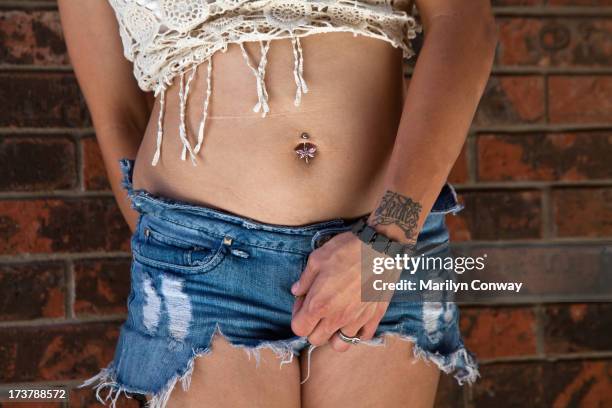 woman with belly button piercing in cut off jeans - belly button piercing foto e immagini stock