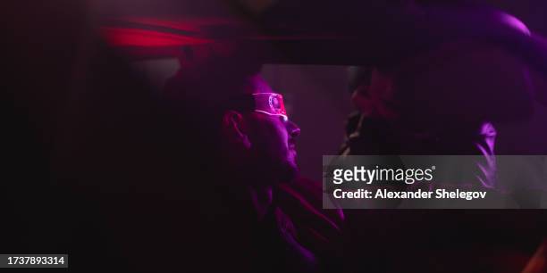 group portrait of people in car. neon light concept photography, futuristic photo with color lighting indoors the vehicle. man is driver, woman is passenger. people with glowing eyeglasses. - cyber punk girl stock pictures, royalty-free photos & images