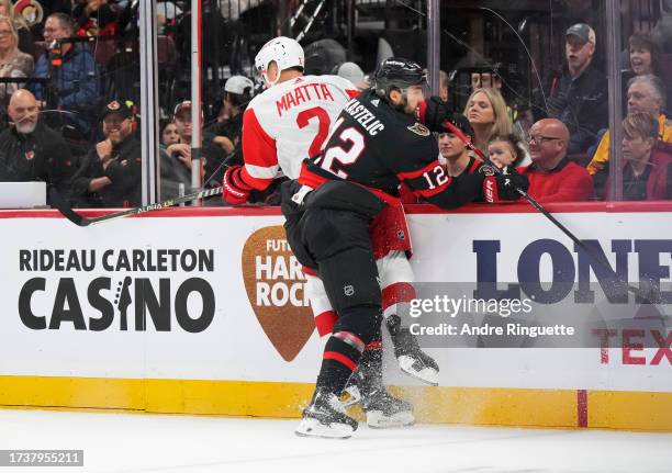 Mark Kastelic of the Ottawa Senators body-checks Olli Maatta of the Detroit Red Wings at Canadian Tire Centre on October 21, 2023 in Ottawa, Ontario,...