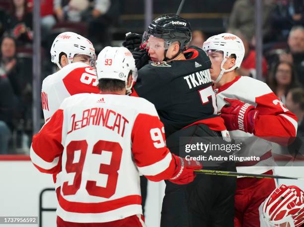 Brady Tkachuk of the Ottawa Senators pushes and shoves with Jake Walman and Lucas Raymond of the Detroit Red Wings as Alex DeBrincat approaches at...