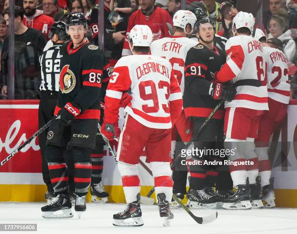 Jake Sanderson of the Ottawa Senators has words with Alex DeBrincat of the Detroit Red Wings as other players push and shove in the corner during a...