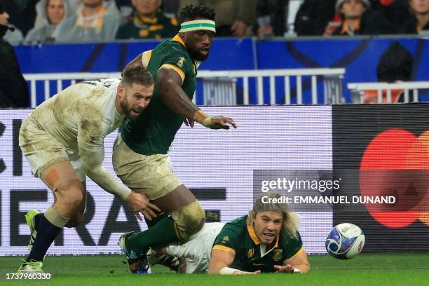 South Africa's scrum-half Faf de Klerk eyes the ball after slipping on the field as South Africa's blindside flanker and captain Siya Kolisi reacts...