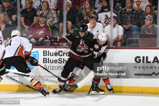 Travis Dermott of the Arizona Coyotes battles for a loose puck with Ryan Strome and Cam Fowler of the Anaheim Ducks during the first period at...