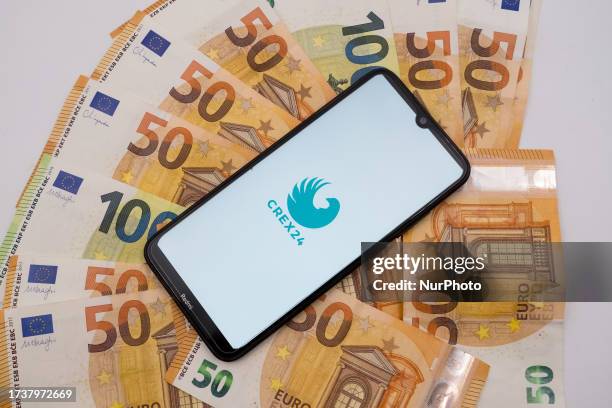 In this photo illustration a Crex24 logo seen displayed on a smartphone screen on 50 and 100 Euro bills in Athens, Greece on October 22, 2023.