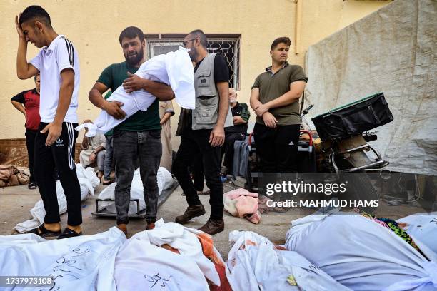 Man reacts as he carries the shrouded body of his child, in front of the morgue of the Al-Aqsa hospital in Deir Balah in the central Gaza Strip,...