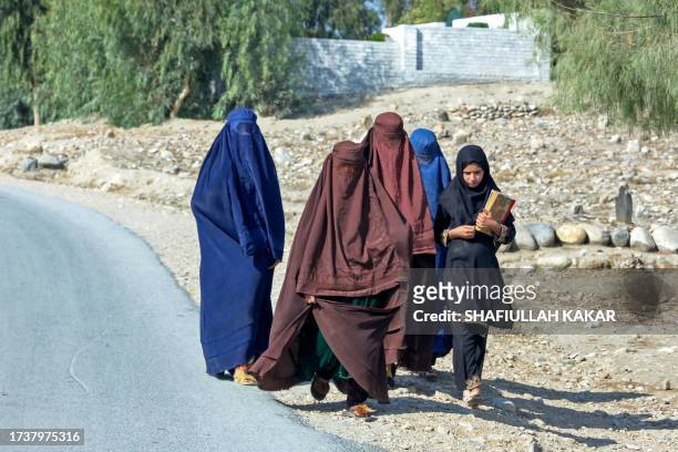 Afghan burqa-clad women walk along a street in the outskirts of Jalalabad on October 22, 2023.