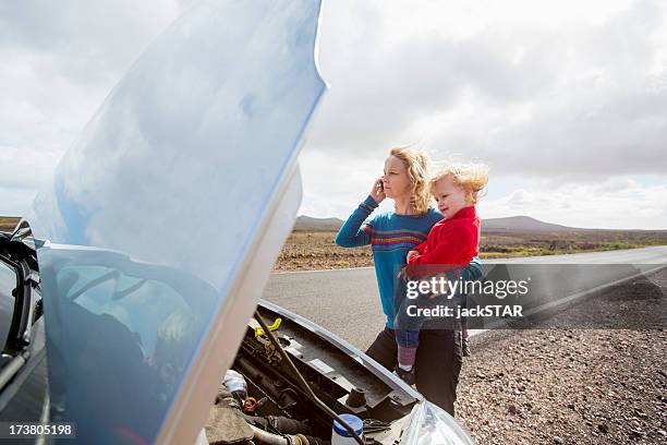 mother and daughter with broken down car - straßenrand stock-fotos und bilder