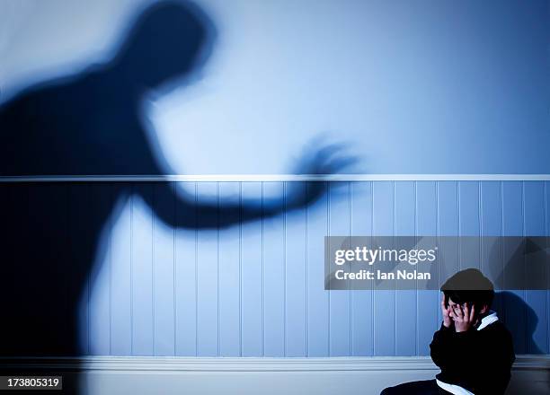 shadow looming over frightened boy - abuse imagens e fotografias de stock