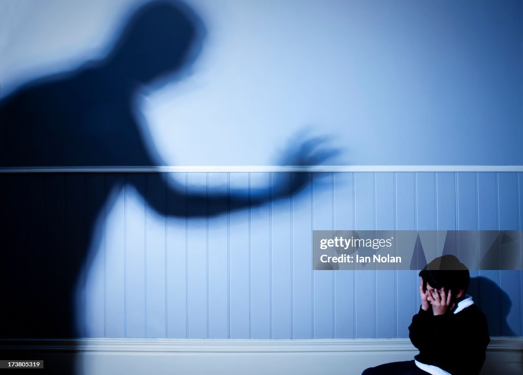 Shadow looming over frightened boy