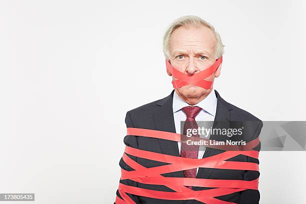 businessman wrapped in red tape - administrative professional stock pictures, royalty-free photos & images