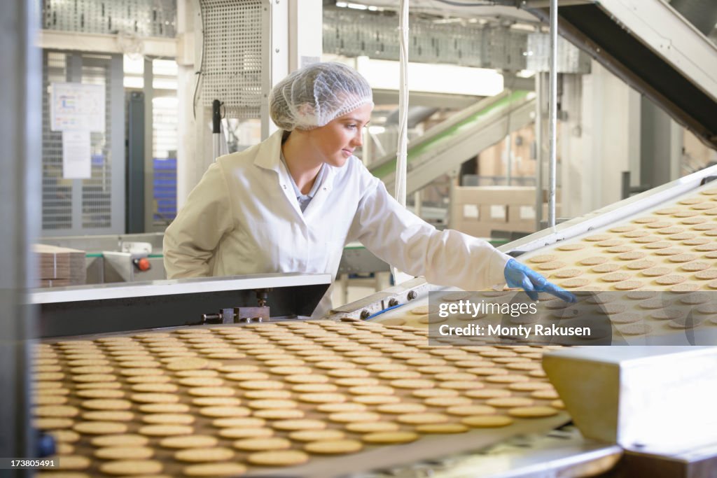 Biscuit factory worker inspecting freshly made biscuits on production line