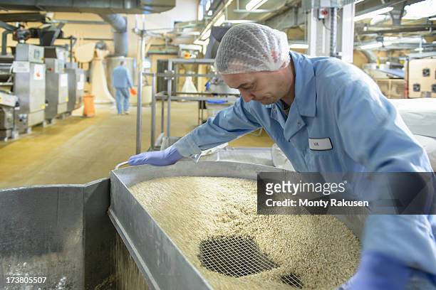 worker mixing ingredients together in biscuit factory - rubber 55 stock-fotos und bilder