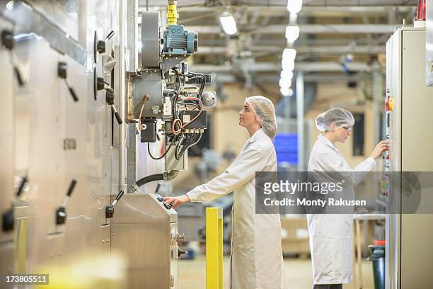 workers attending ovens in biscuit factory - lebensmittelindustrie stock-fotos und bilder