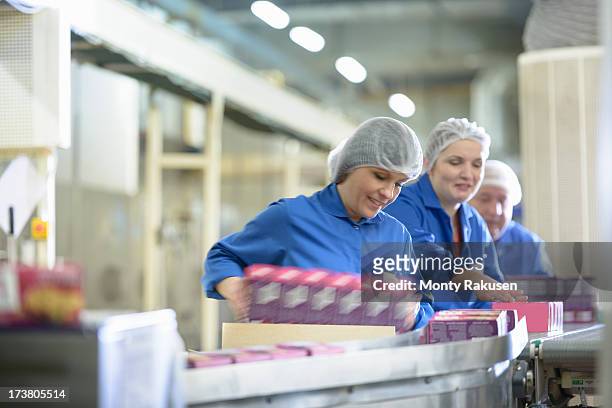 workers on packing line in biscuit factory - man with moving boxes authentic stockfoto's en -beelden