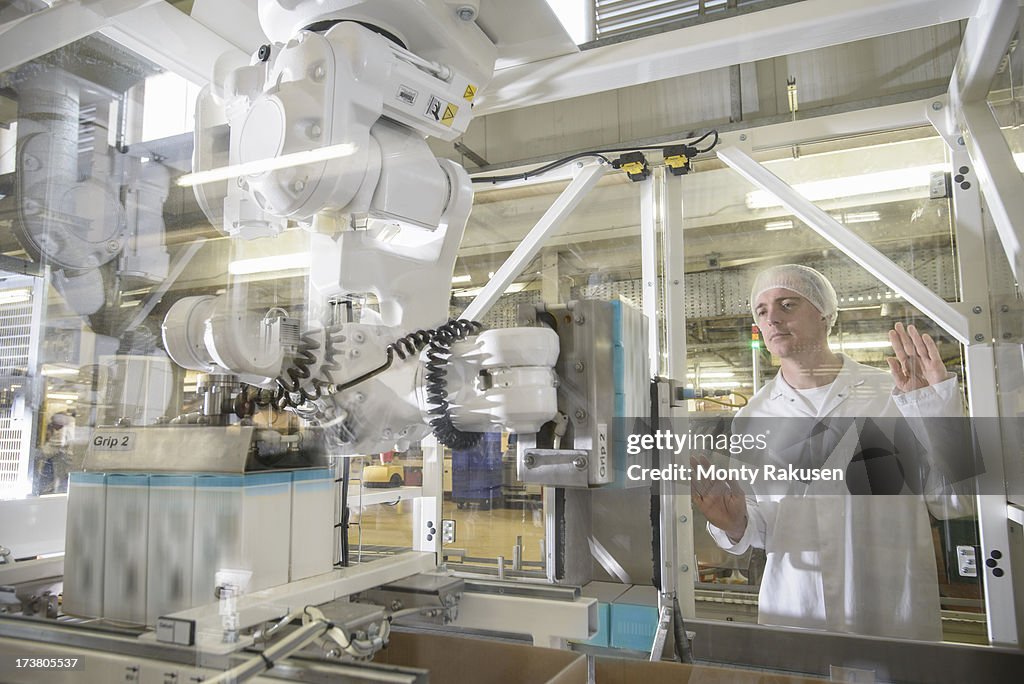 Worker watching robotic packing machine in biscuit factory