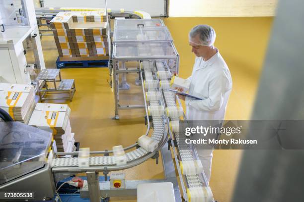 worker inspecting packed products on conveyor belt in biscuit factory - boxes conveyor belt stockfoto's en -beelden