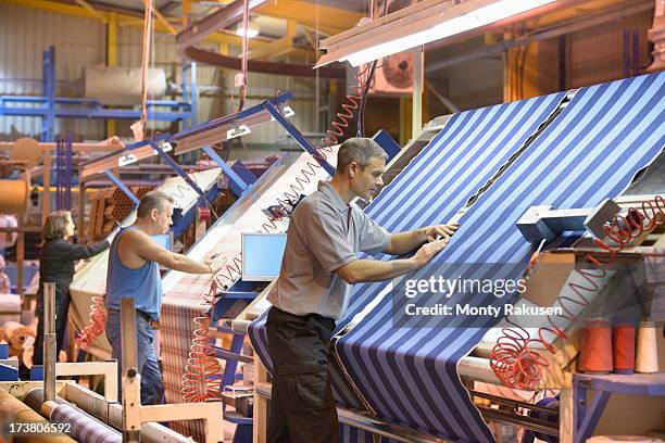 textile workers inspecting striped woven thread in mill - fábrica textil fotografías e imágenes de stock