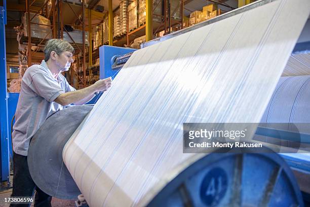 textile worker winding yarn on industrial loom in mill - textile industry uk stock pictures, royalty-free photos & images