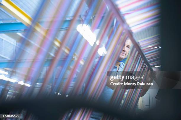 worker inspecting multicoloured threads on industrial loom in textile mill - loom stock pictures, royalty-free photos & images