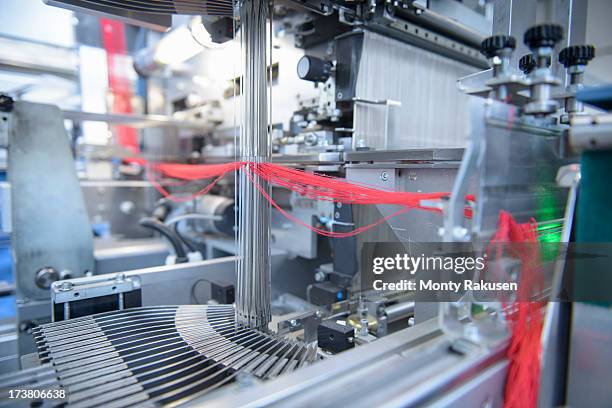 red yarn passing through threading machine in textile mill - roter faden stock-fotos und bilder