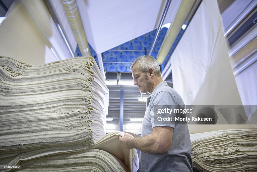 Worker using finishing machinery in textile mill