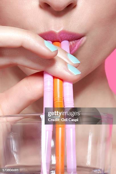 close up of woman drinking with straws - rietje stockfoto's en -beelden