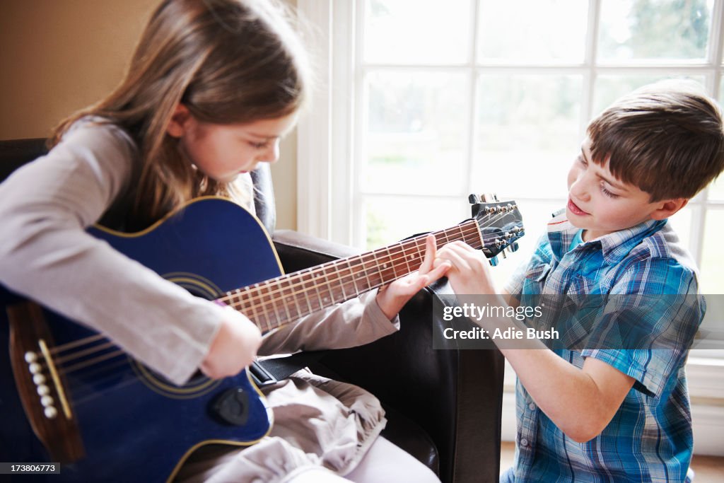 Boy helping girl play guitar