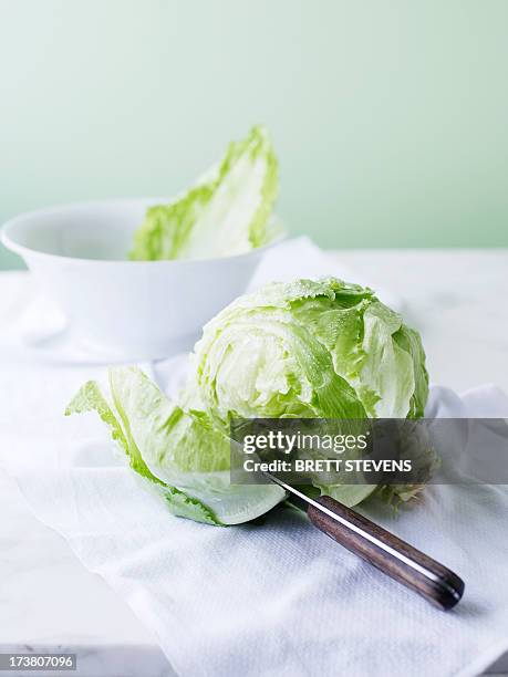 knife slicing through head of lettuce - iceberg lettuce stock pictures, royalty-free photos & images