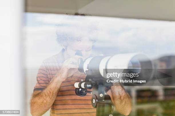 man using telescope at window - 望遠鏡　男性 ストックフォトと画像