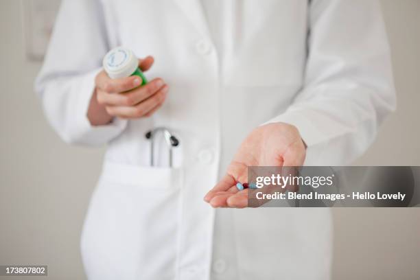 doctor holding handful of pills - drug bust stock pictures, royalty-free photos & images