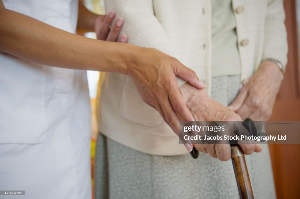 Close up of caretaker helping older woman walk