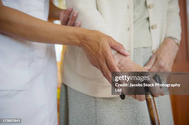 close up of caretaker helping older woman walk - patient safety - fotografias e filmes do acervo