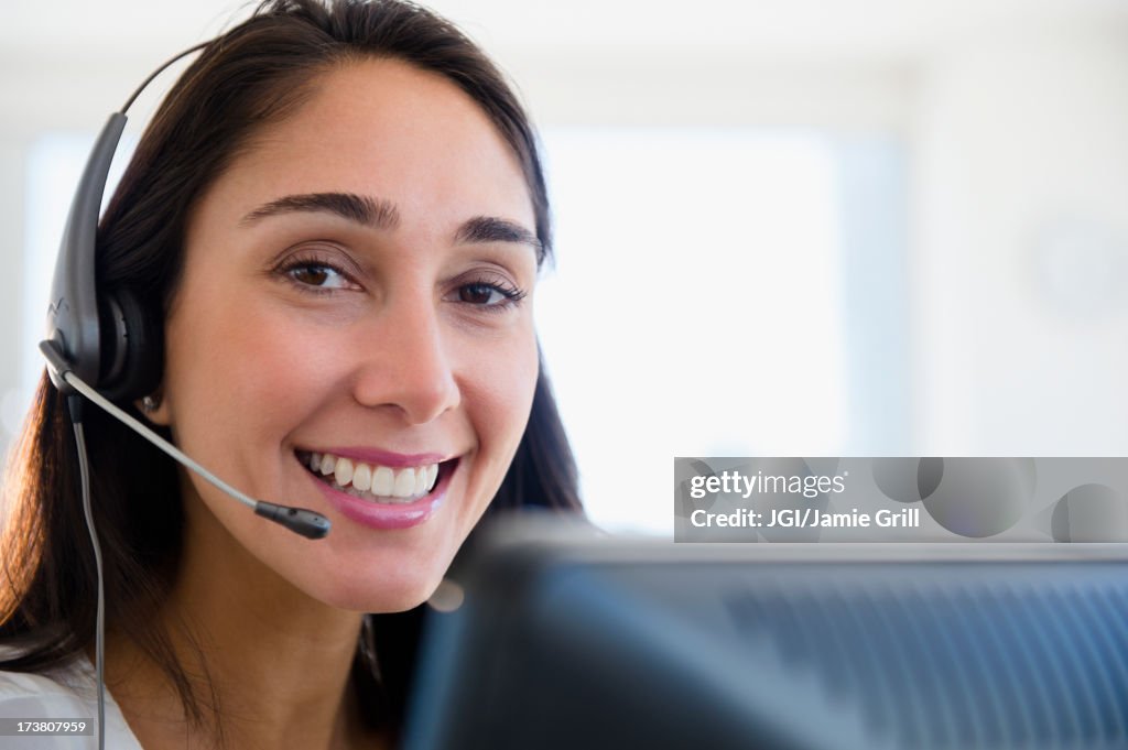 Caucasian businesswoman wearing headset at desk