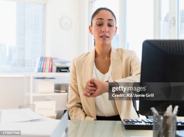 caucasian businesswoman checking watch at desk - leaving work stock pictures, royalty-free photos & images