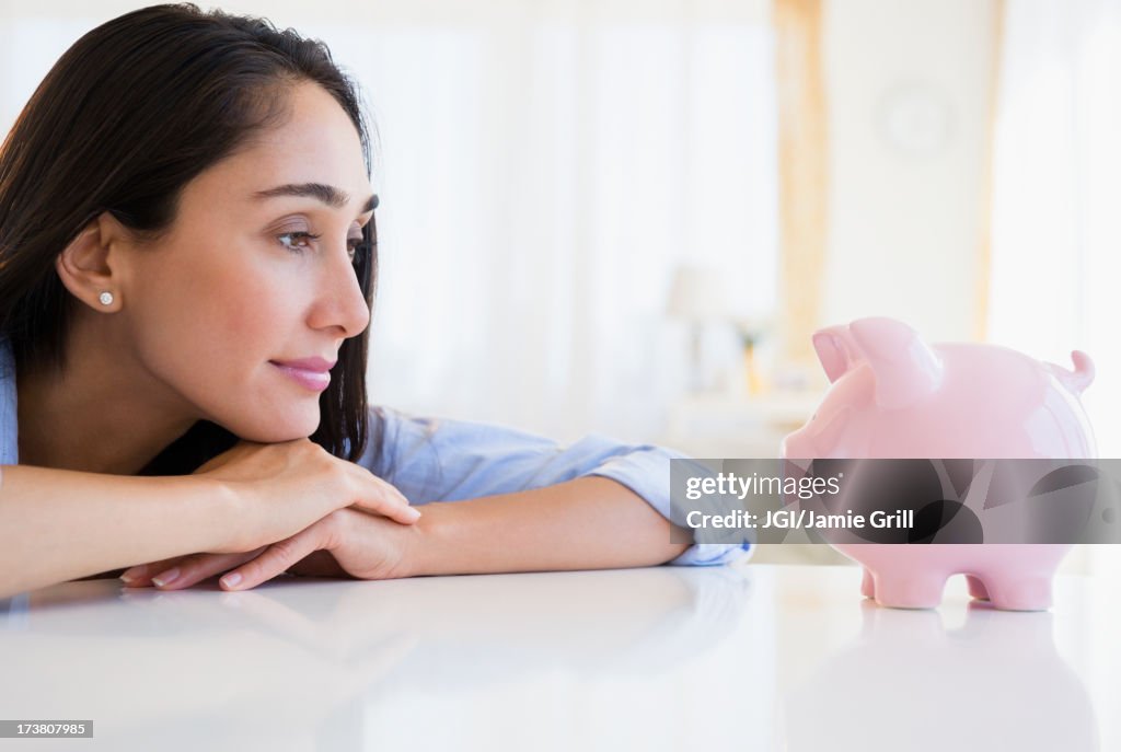 Caucasian businesswoman examining piggy bank